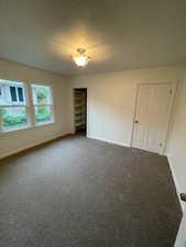 Empty room with baseboards and dark colored carpet