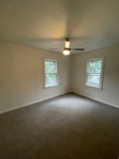 Empty room featuring plenty of natural light, dark colored carpet, and baseboards