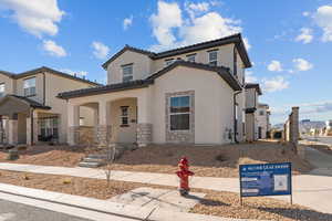 Mediterranean / spanish-style home with stucco siding, covered porch, stone siding, and a tiled roof