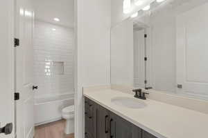 Full bath featuring toilet, vanity, wood finished floors, and bathtub / shower combination