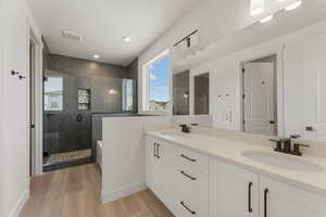 Bathroom featuring a shower stall, wood finished floors, double vanity, recessed lighting, and a tub