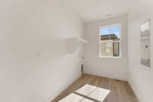 Laundry room with baseboards, light wood-style floors, washer hookup, electric panel, and electric dryer hookup