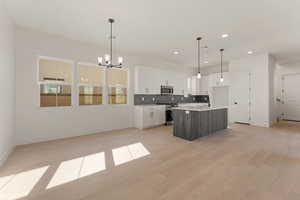 Kitchen with stainless steel appliances, a chandelier, baseboards, decorative backsplash, and recessed lighting