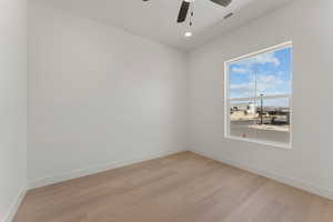 Empty room with light wood-style floors, ceiling fan, baseboards, and recessed lighting