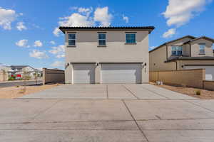 View of front of home with an attached garage, stucco siding, concrete driveway, and a tiled roof