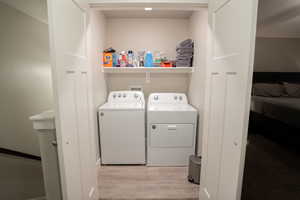 Laundry area with washer and dryer and light wood finished floors