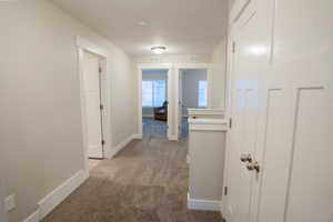 Corridor with carpet, baseboards, and a textured ceiling