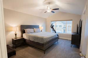 Carpeted bedroom featuring vaulted ceiling, ceiling fan, and baseboards