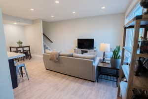 Living area with stairway, light wood-type flooring, recessed lighting, and baseboards