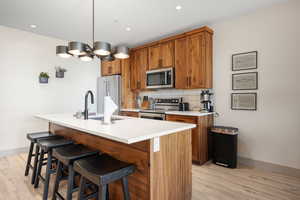 Kitchen with appliances with stainless steel finishes, brown cabinetry, light wood-style floors, and recessed lighting