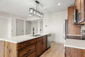 Kitchen featuring a sink, stainless steel appliances, brown cabinets, light wood-type flooring, and recessed lighting