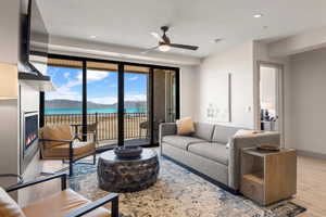 Living area featuring ceiling fan, wood finished floors, a lit fireplace, a water view, and recessed lighting