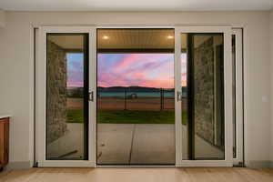 Doorway to outside with light wood finished floors and healthy amount of natural light