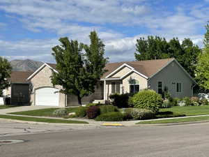 Ranch-style home featuring driveway, an attached garage, stucco siding, a mountain view, and a front yard