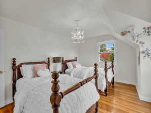 Bedroom with baseboards, light wood finished floors, and a chandelier