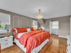 Bedroom with a chandelier, light wood-style flooring, and baseboards