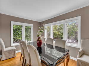 Dining area featuring plenty of natural light, light wood finished floors, baseboards, and ornamental molding