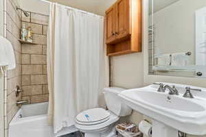 Full bathroom featuring toilet, shower / bath combination with curtain, and a sink