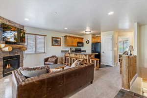 Carpeted living area with a fireplace, a textured ceiling, baseboards, and recessed lighting