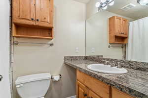 Full bathroom featuring toilet, vanity, and baseboards