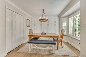 Dining space featuring a chandelier, light wood-style flooring, crown molding, and baseboards