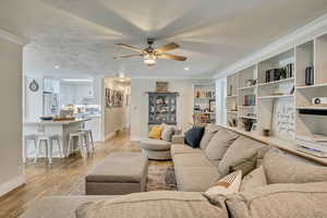 Living area with crown molding, ceiling fan, light wood-type flooring, baseboards, and recessed lighting