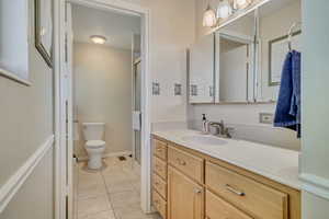 Bathroom with toilet, tile patterned floors, vanity, and a stall shower