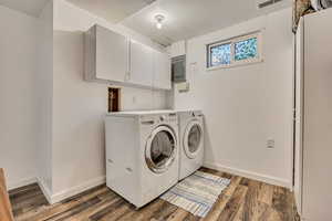 Washroom featuring cabinet space, washing machine and dryer, baseboards, electric panel, and wood finished floors