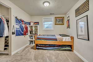 Bedroom with carpet floors, a textured ceiling, and baseboards