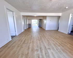 Spare room with a textured ceiling, light wood finished floors, and baseboards