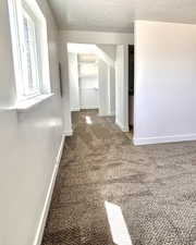 Corridor with carpet, baseboards, and a textured ceiling