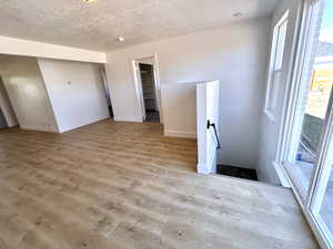 Spare room featuring light wood-type flooring, baseboards, and a textured ceiling