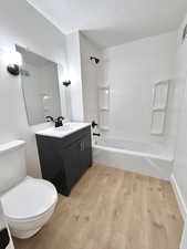 Full bathroom with wood finished floors, shower / bathtub combination, toilet, and vanity