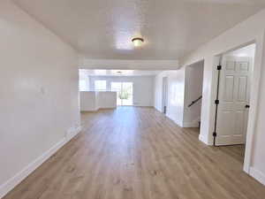 Empty room with baseboards, light wood finished floors, and a textured ceiling