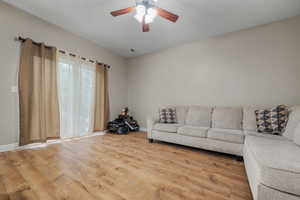 Living room featuring light wood-style flooring, ceiling fan, and baseboards