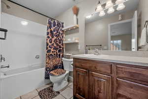Full bathroom with tile patterned floors, toilet, vanity, and shower / tub combo with curtain