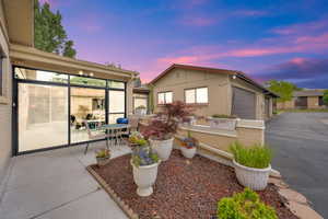 View of front facade featuring asphalt driveway, an attached garage, an outdoor structure, and a patio