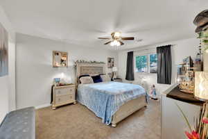 Bedroom featuring light carpet, a ceiling fan, and baseboards