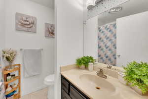 Bathroom featuring toilet, vanity, tile patterned floors, and curtained shower
