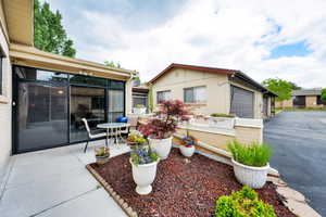View of patio / terrace featuring a garage, a sunroom, and driveway