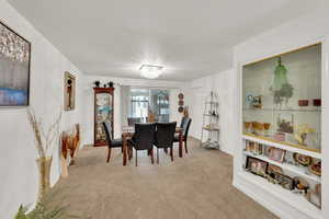Carpeted dining space featuring a chandelier and baseboards