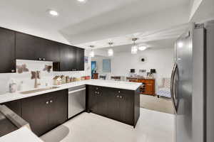 Kitchen with appliances with stainless steel finishes, a sink, a peninsula, light countertops, and recessed lighting