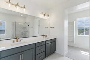 Full bathroom featuring a marble finish shower, baseboards, double vanity, and tile patterned flooring