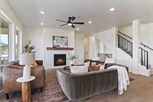 Living room featuring light wood-style flooring, a fireplace, stairway, recessed lighting, and ceiling fan