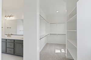 Walk in closet with light colored carpet and a sink