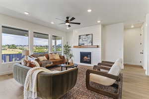 Living room with light wood-style floors, a large fireplace, recessed lighting, ceiling fan, and a textured ceiling