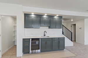 Bar featuring beverage cooler, a sink, light colored carpet, baseboards, and recessed lighting