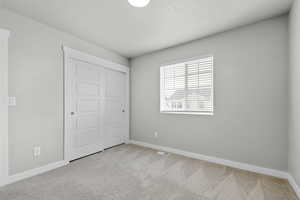Unfurnished bedroom featuring carpet floors, baseboards, a closet, and a textured ceiling