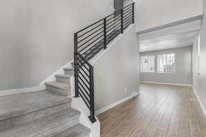 Staircase with wood finished floors and baseboards