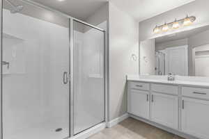 Bathroom with a stall shower, baseboards, and vanity